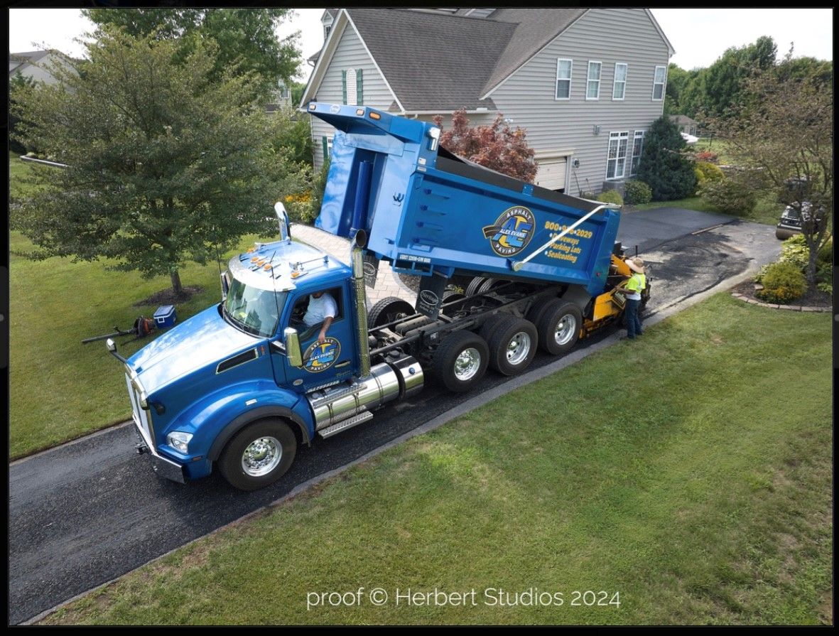 A yellow truck is driving down a road next to a building.