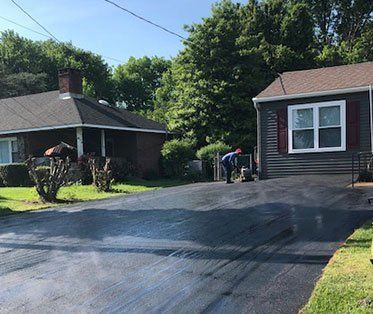 A man is paving a driveway in front of a house.