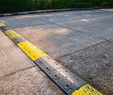 A yellow and black speed bump on the side of a road.