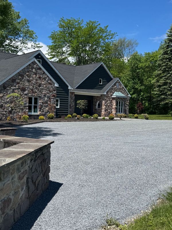 A large stone house with a gravel driveway in front of it.