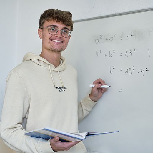 Nachhilfe Lehrer Lerntreff Sympathischer Nachhilfe Lehrer schreibt mit einem Stift auf eine weiße Tafel