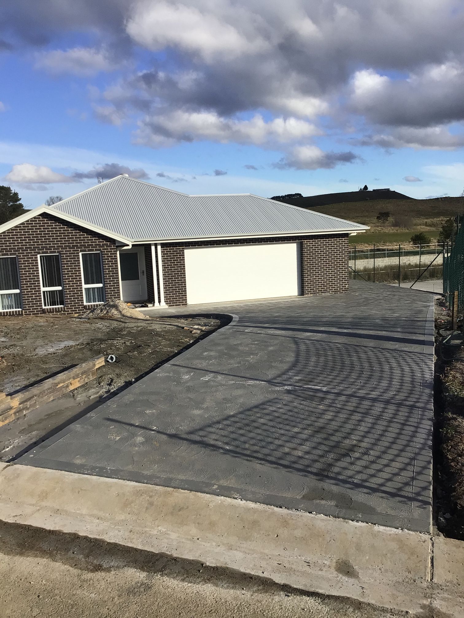 Well-maintained coal tar driveway in front of a house, providing a smooth and convenient entrance — About Time Plumbing & Civil Construction in Moss Vale, NSW