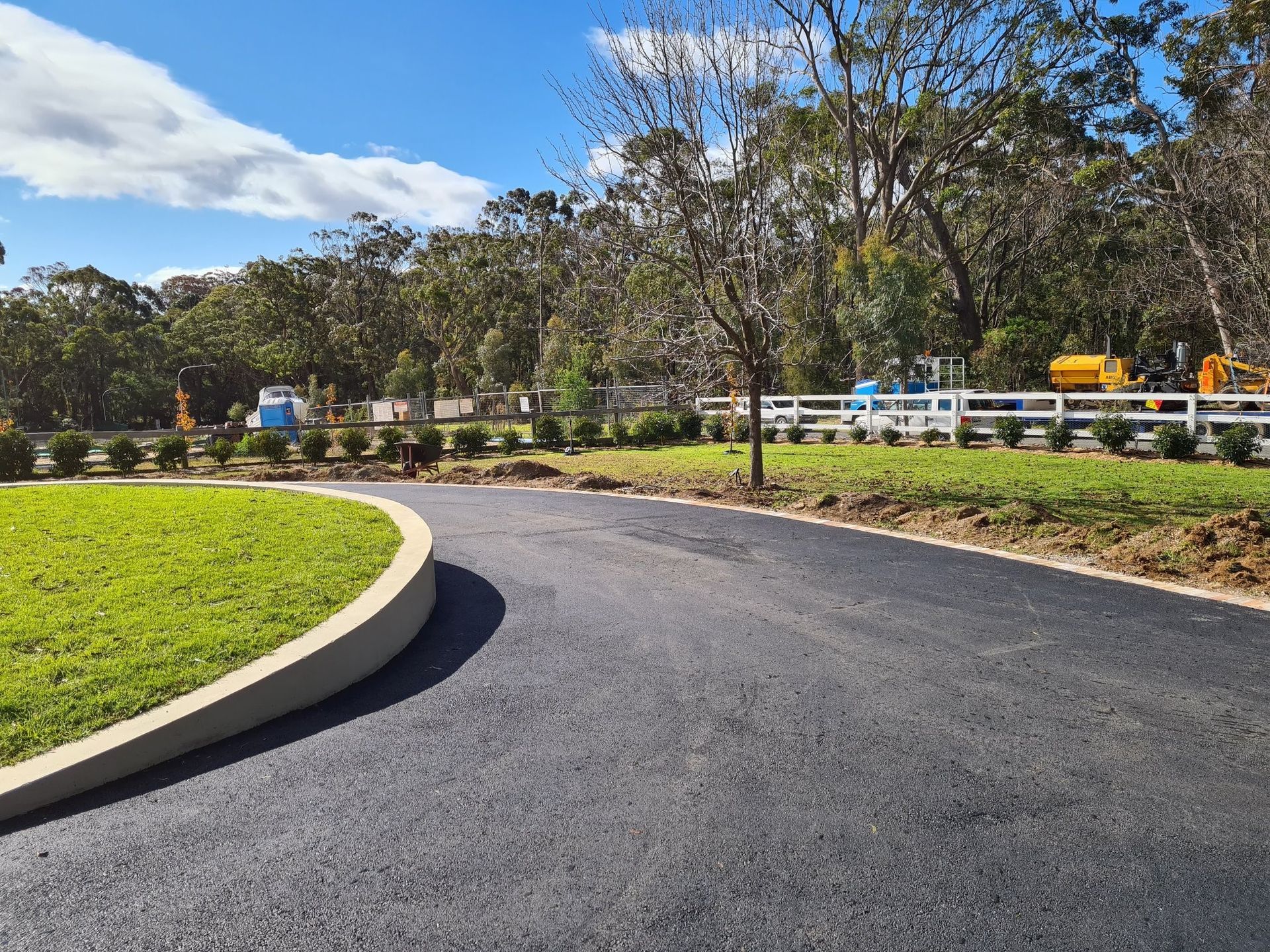 A Curvy Road Going Through A Grassy Field With A White Fence — About Time Plumbing & Civil Construction in Moss Vale, NSW
