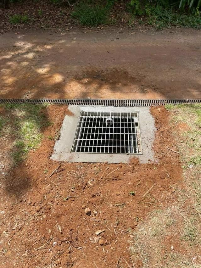 A Manhole Cover Is Sitting In The Dirt Next To A Path — About Time Plumbing & Civil Construction in Moss Vale, NSW