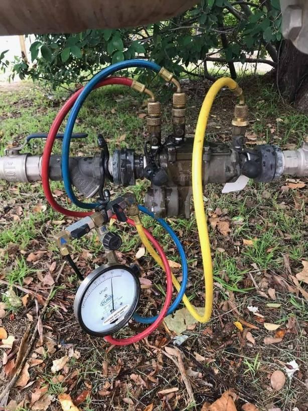 A Pressure Gauge Is Attached To A Pipe In The Grass — About Time Plumbing & Civil Construction in Moss Vale, NSW