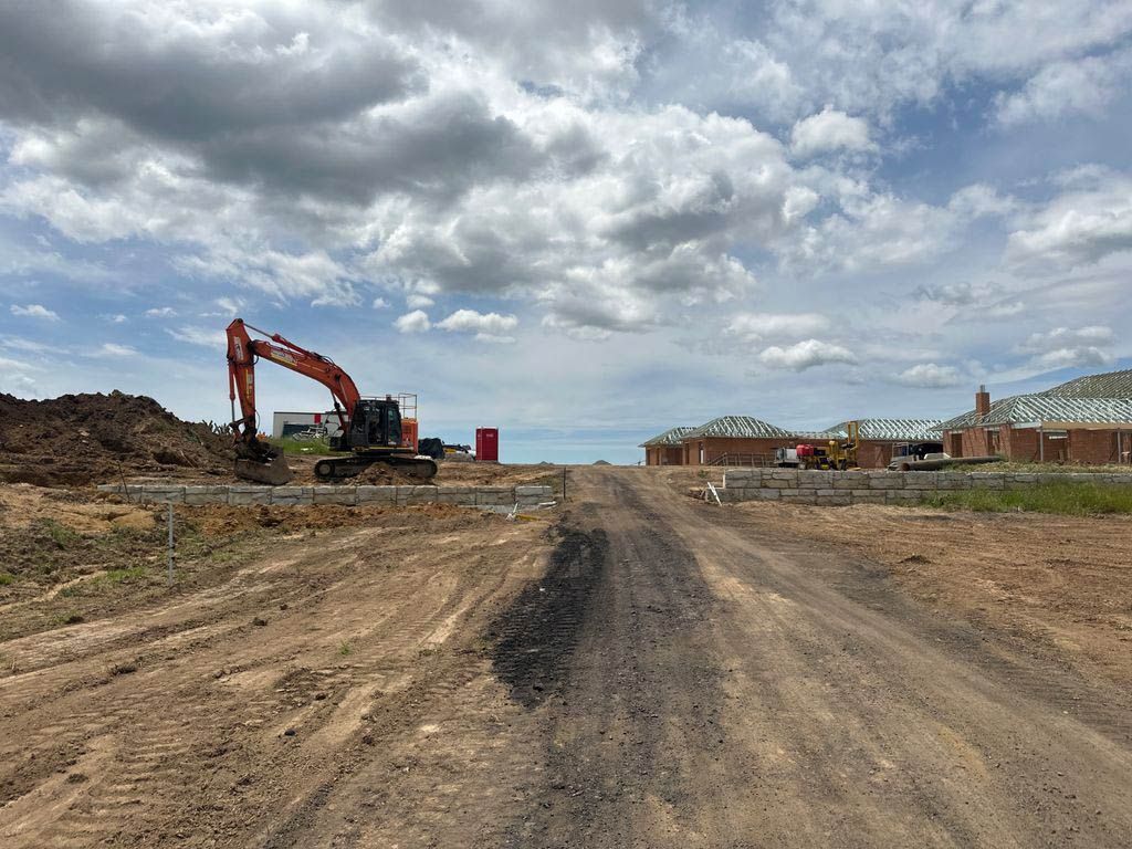 An Excavator Is Working On A Dirt Road In A Construction Site — About Time Plumbing & Civil Construction in Moss Vale, NSW