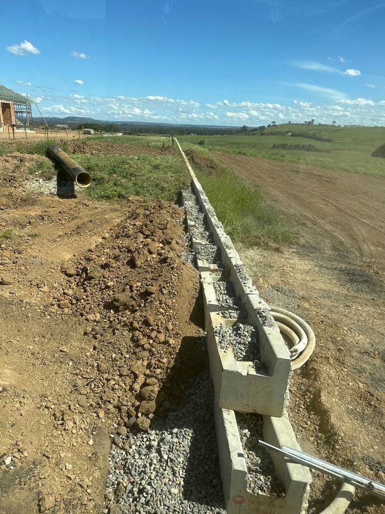 A Concrete Wall Is Being Built In A Dirt Field — About Time Plumbing & Civil Construction in Moss Vale, NSW