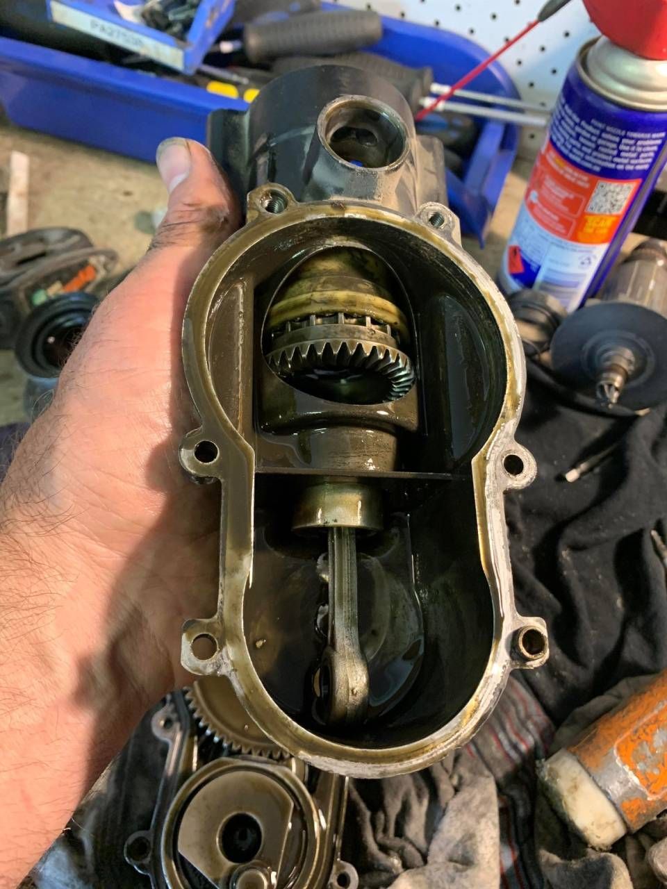 Open engine component held in hand, revealing gears and shaft.