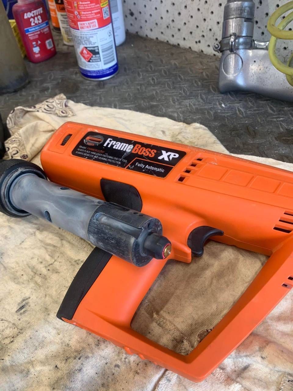 Orange and black FrameBoss XP pneumatic tool on a work surface.