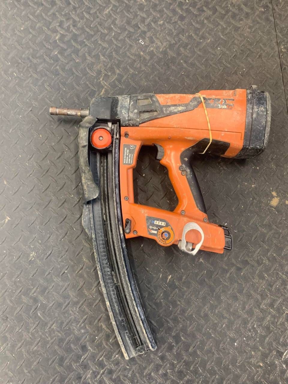 Orange and black nail gun on a black surface.