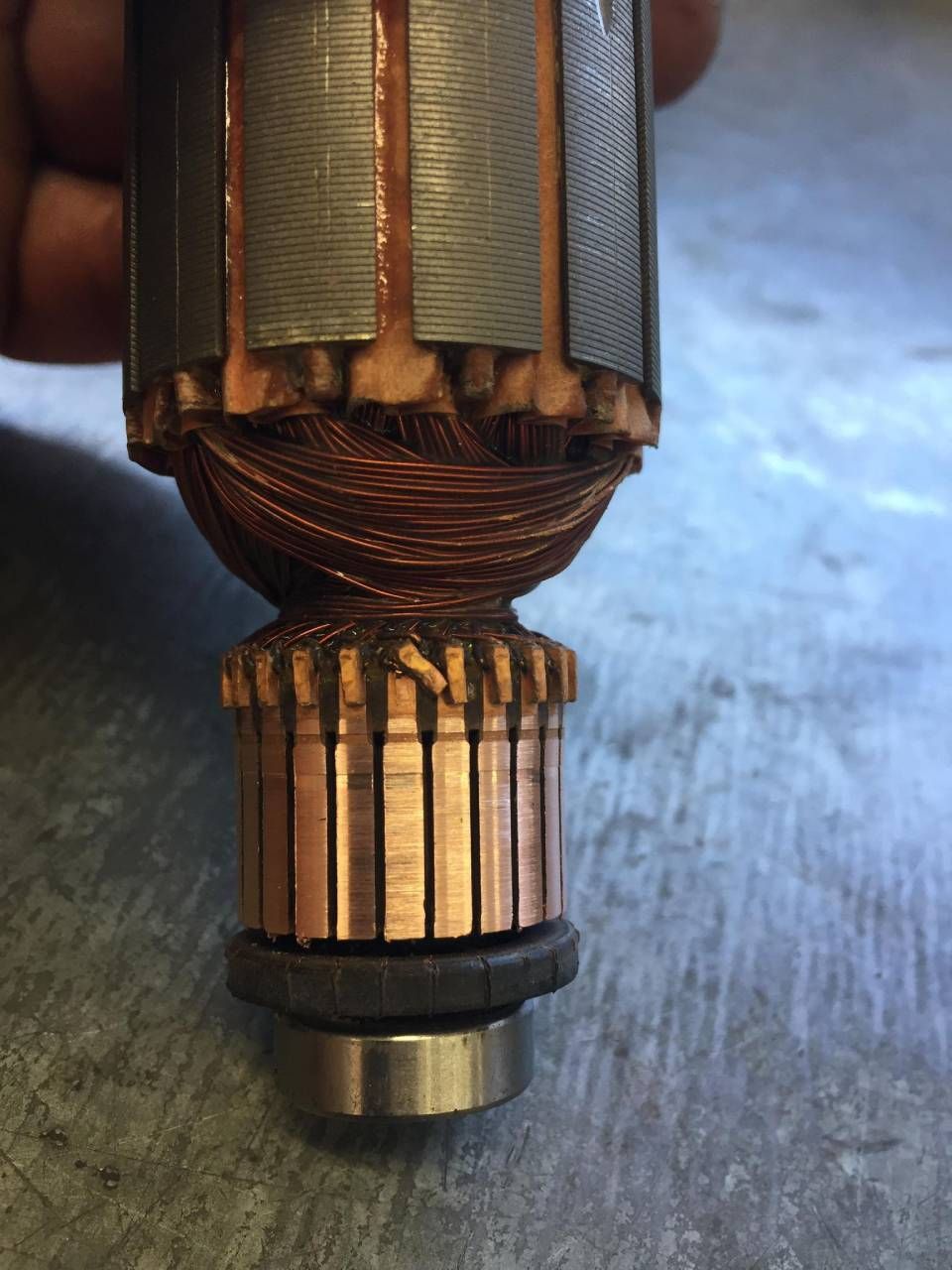 Close-up of a motor's armature, showing copper commutator, wound coils, and metal core.