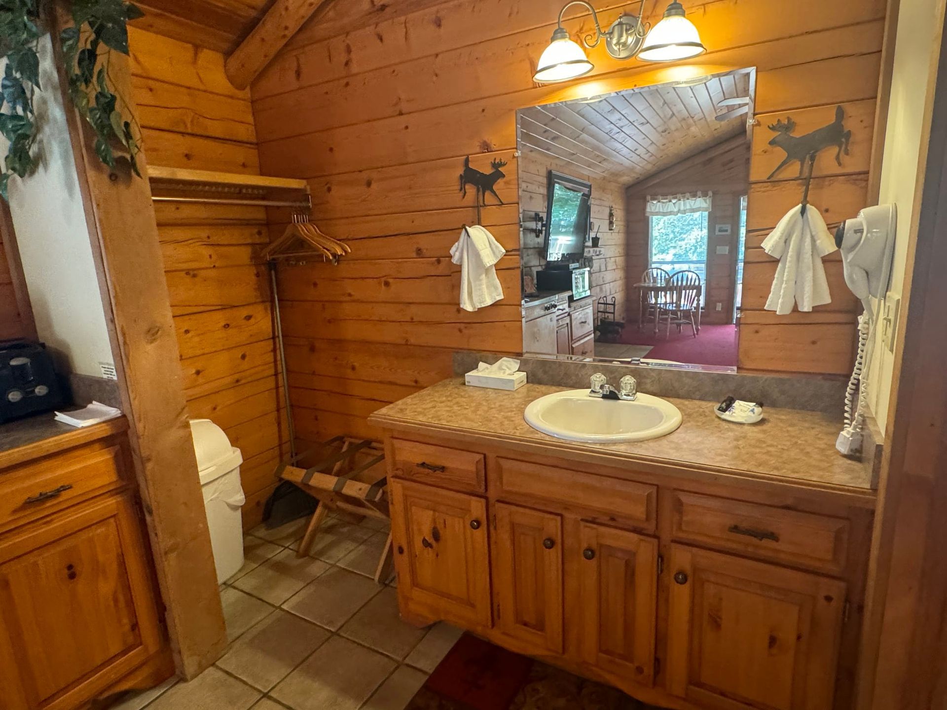 A bathroom in a log cabin with a sink , mirror and cabinets.