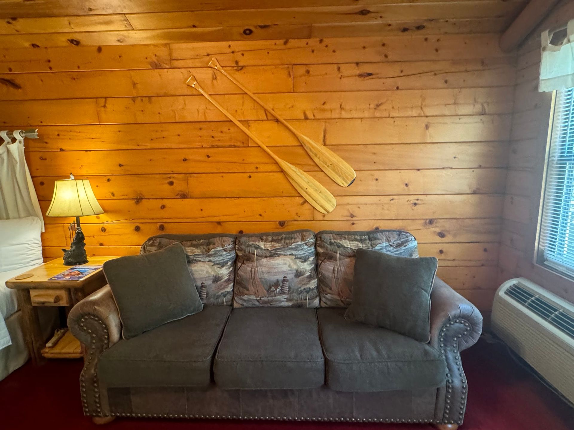 A living room with a couch and two oars on the wall.