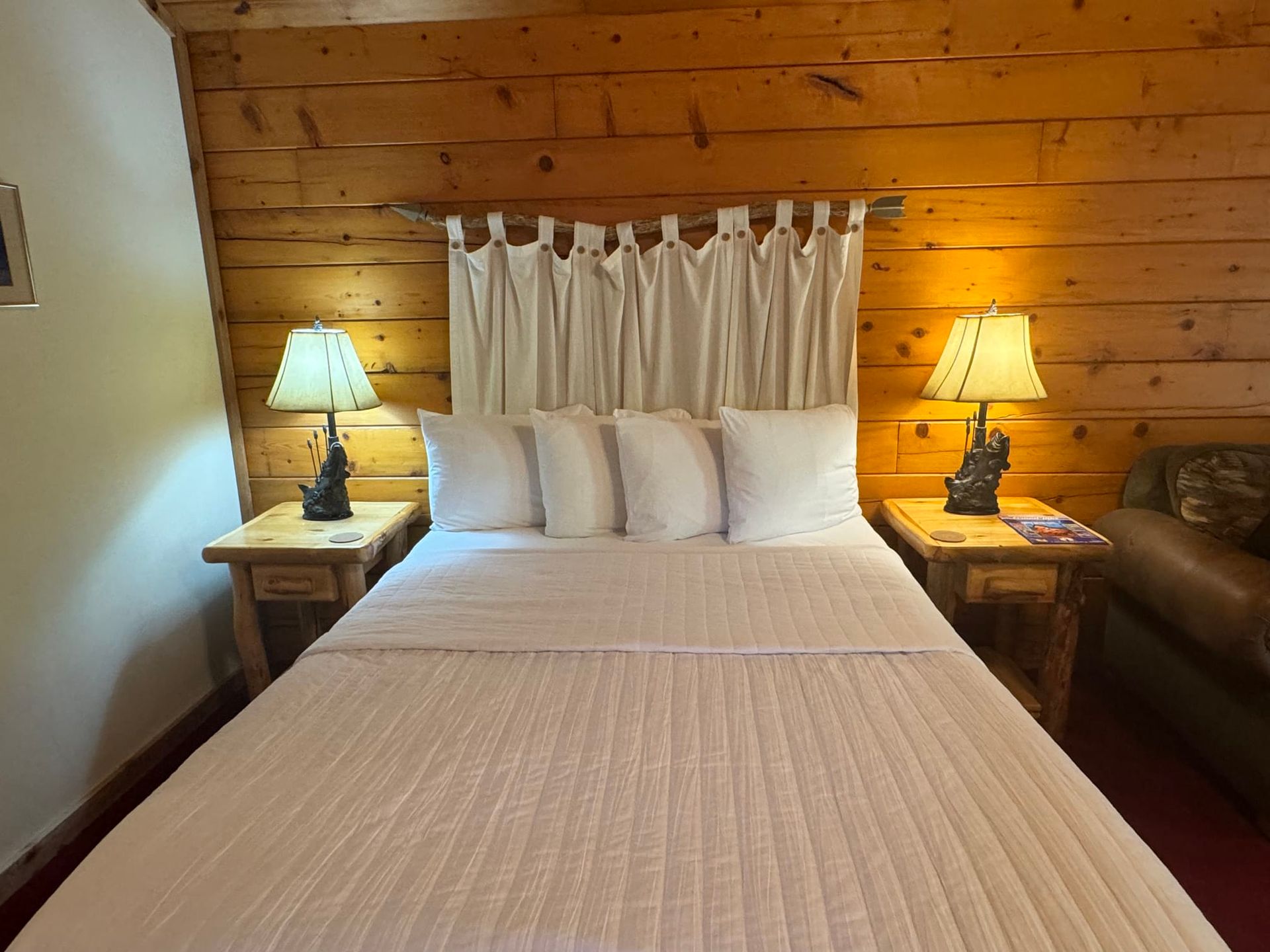 A bedroom with a bed , two lamps and a couch