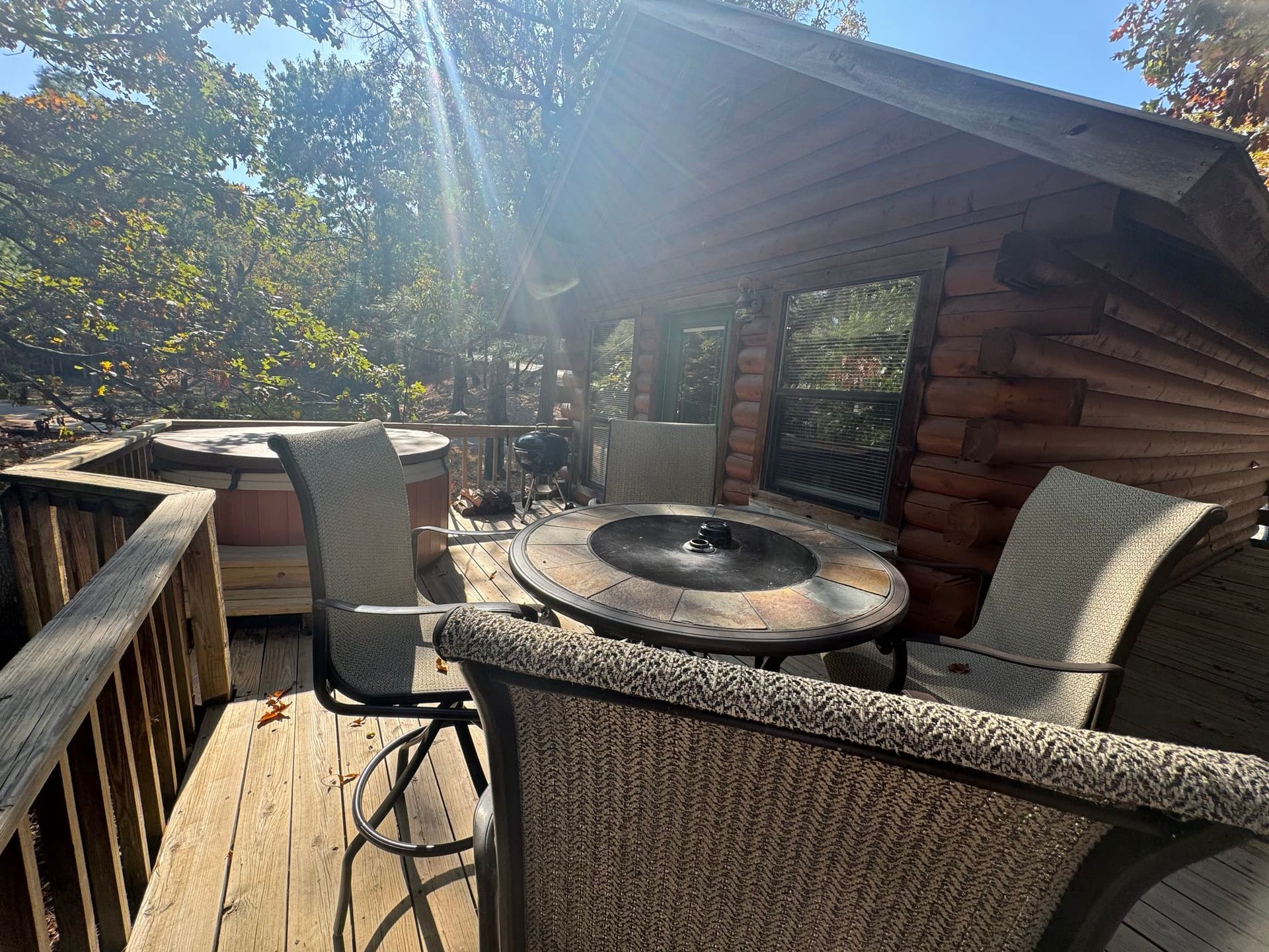 There is a table and chairs on the deck of a log cabin.