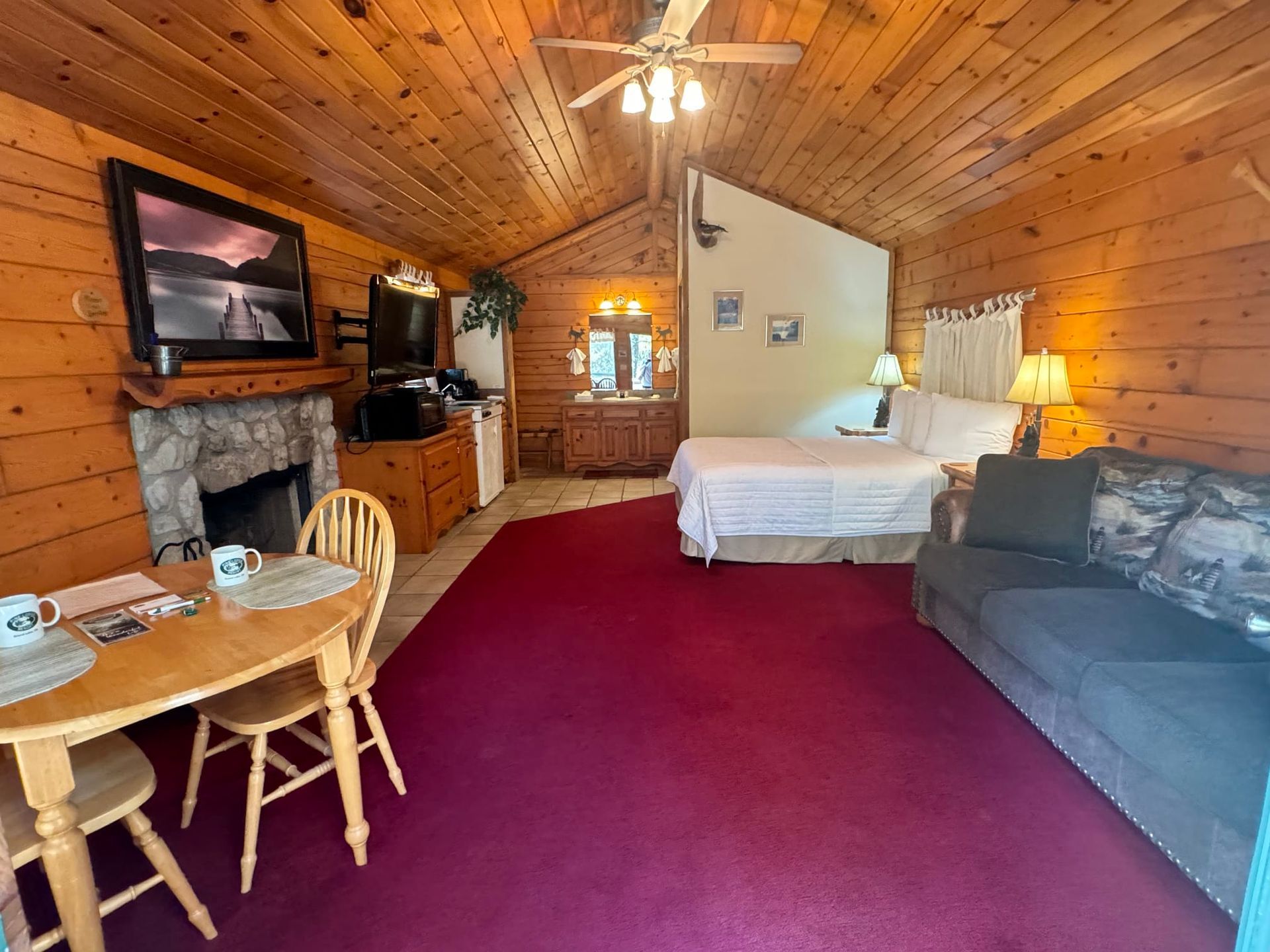 A cabin with a bed , couch , table and fireplace.