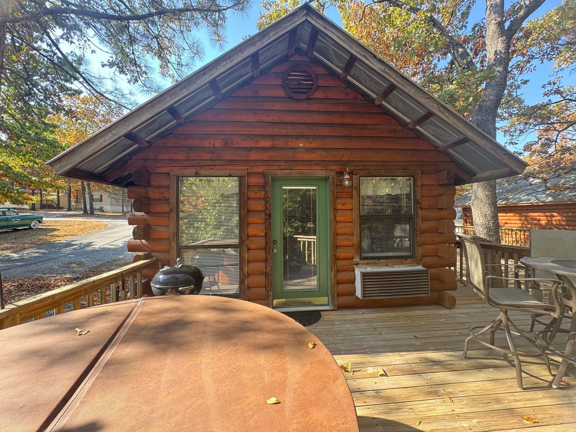A small log cabin with a green door and a table in front of it.