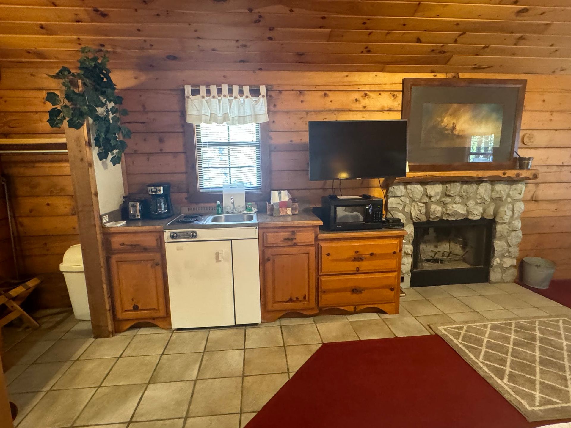A kitchen in a log cabin with a fireplace and a television