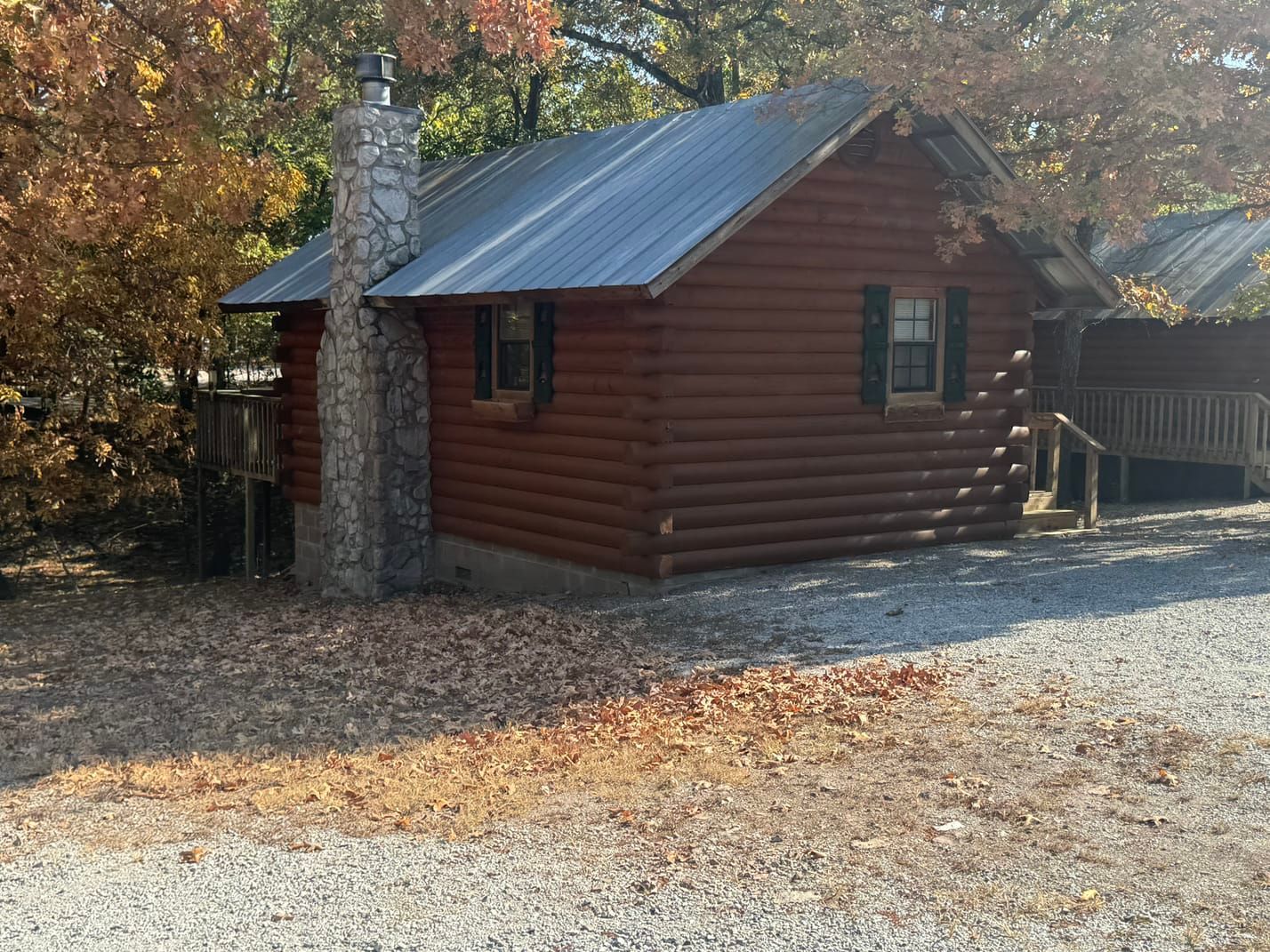 A small log cabin is sitting in the middle of a gravel road.