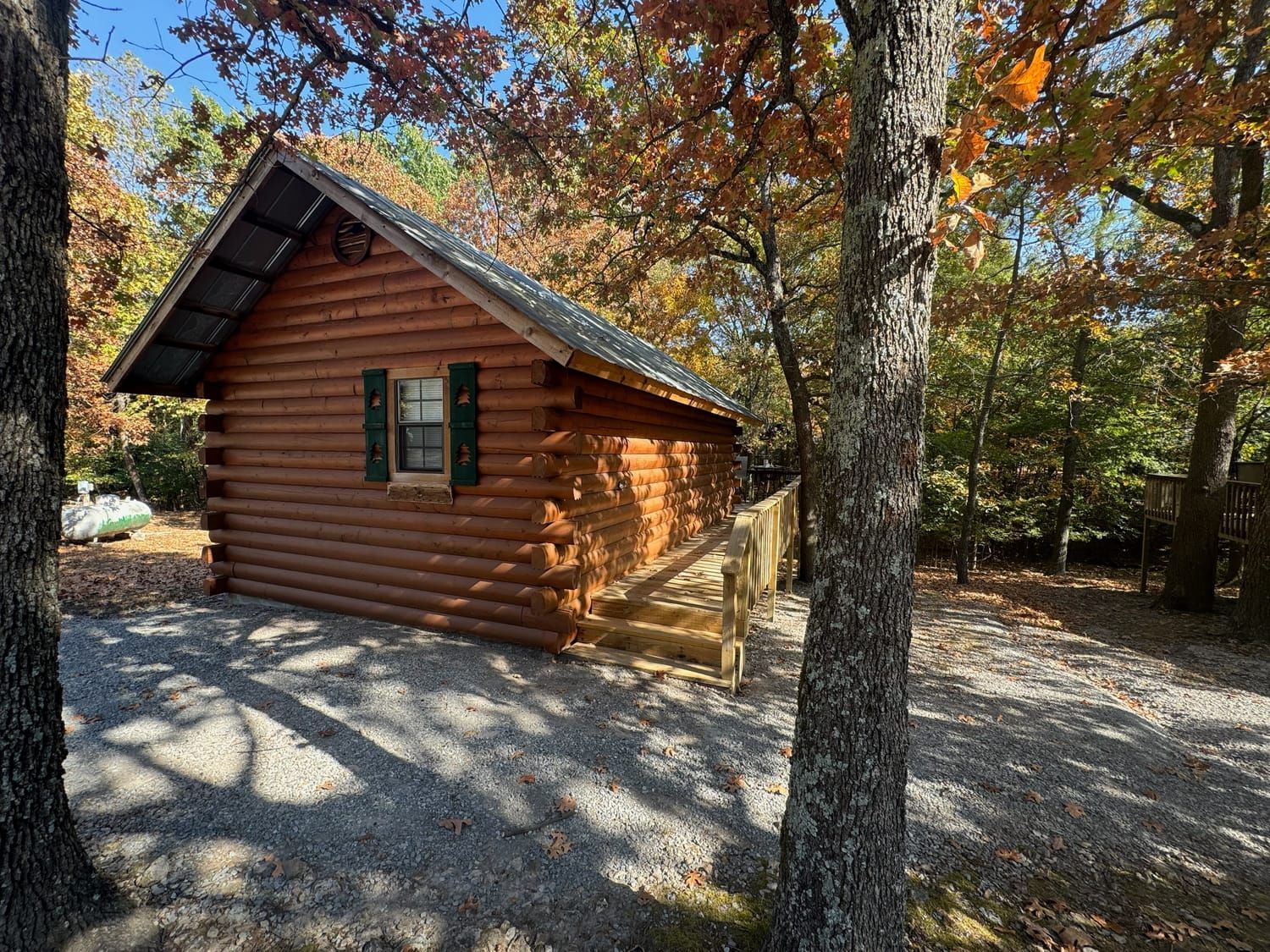 A small log cabin is surrounded by trees in the woods.