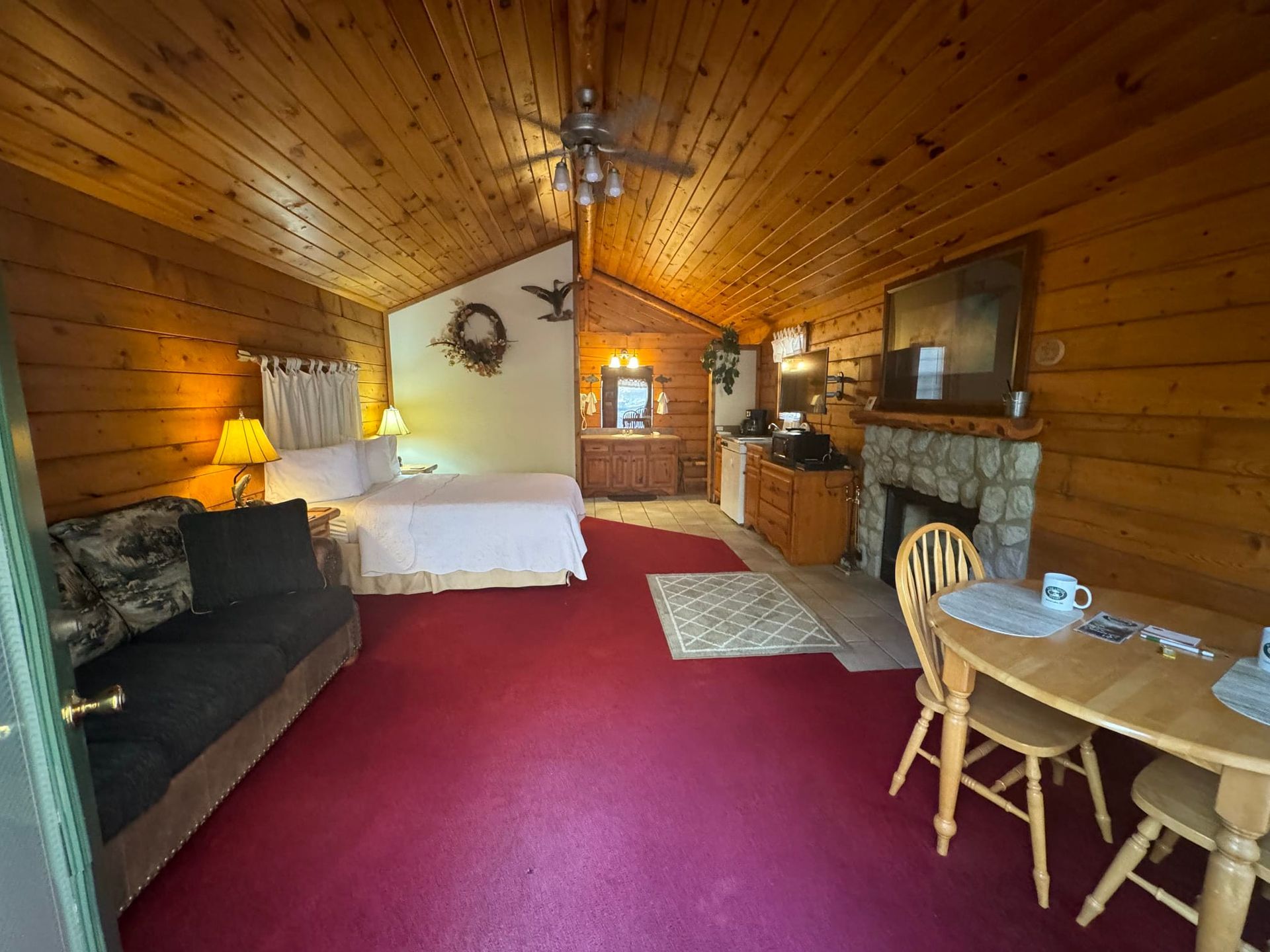 A log cabin with a bed , couch , table and chairs.