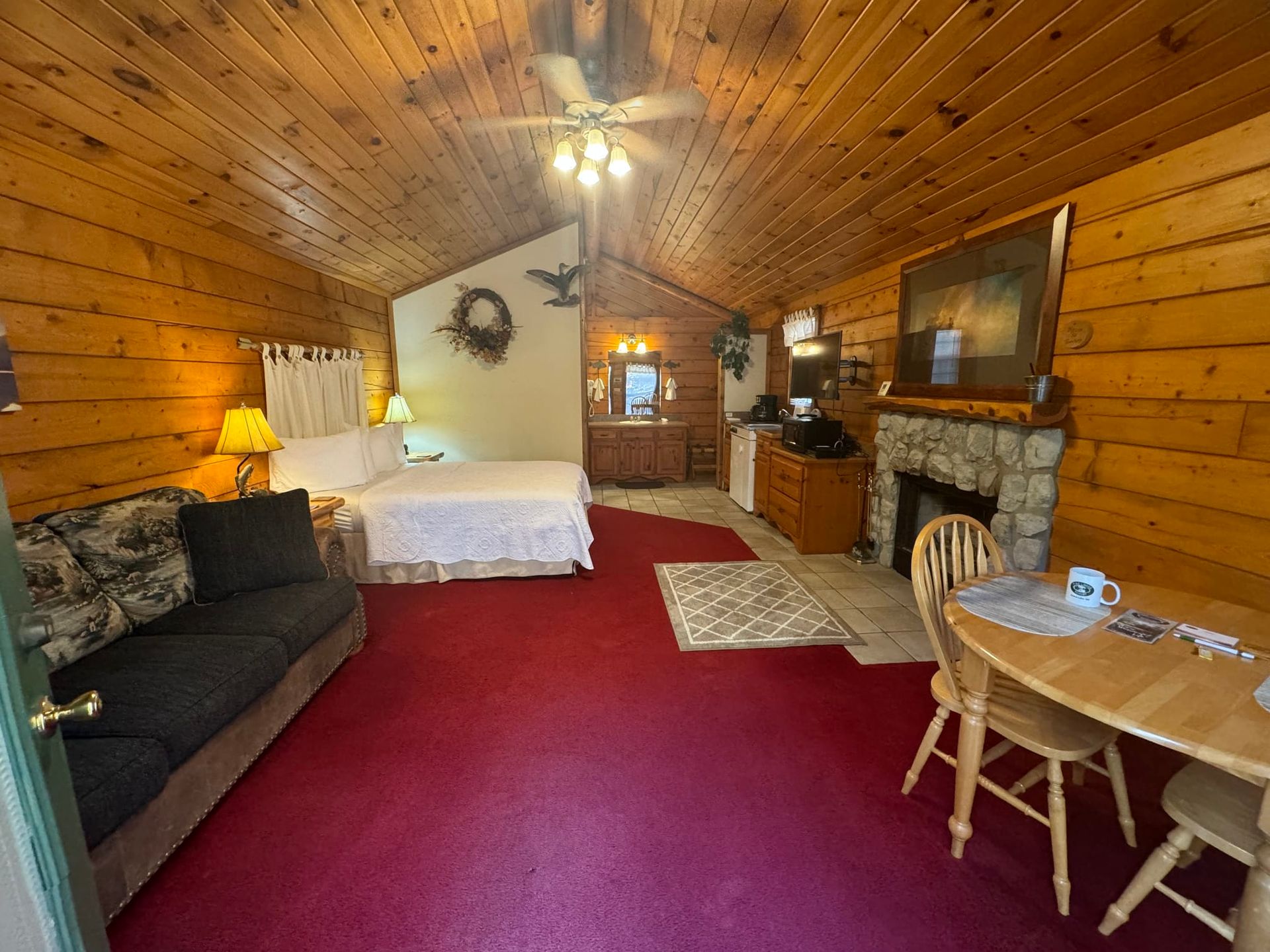 A log cabin with a bed , couch , table and fireplace.