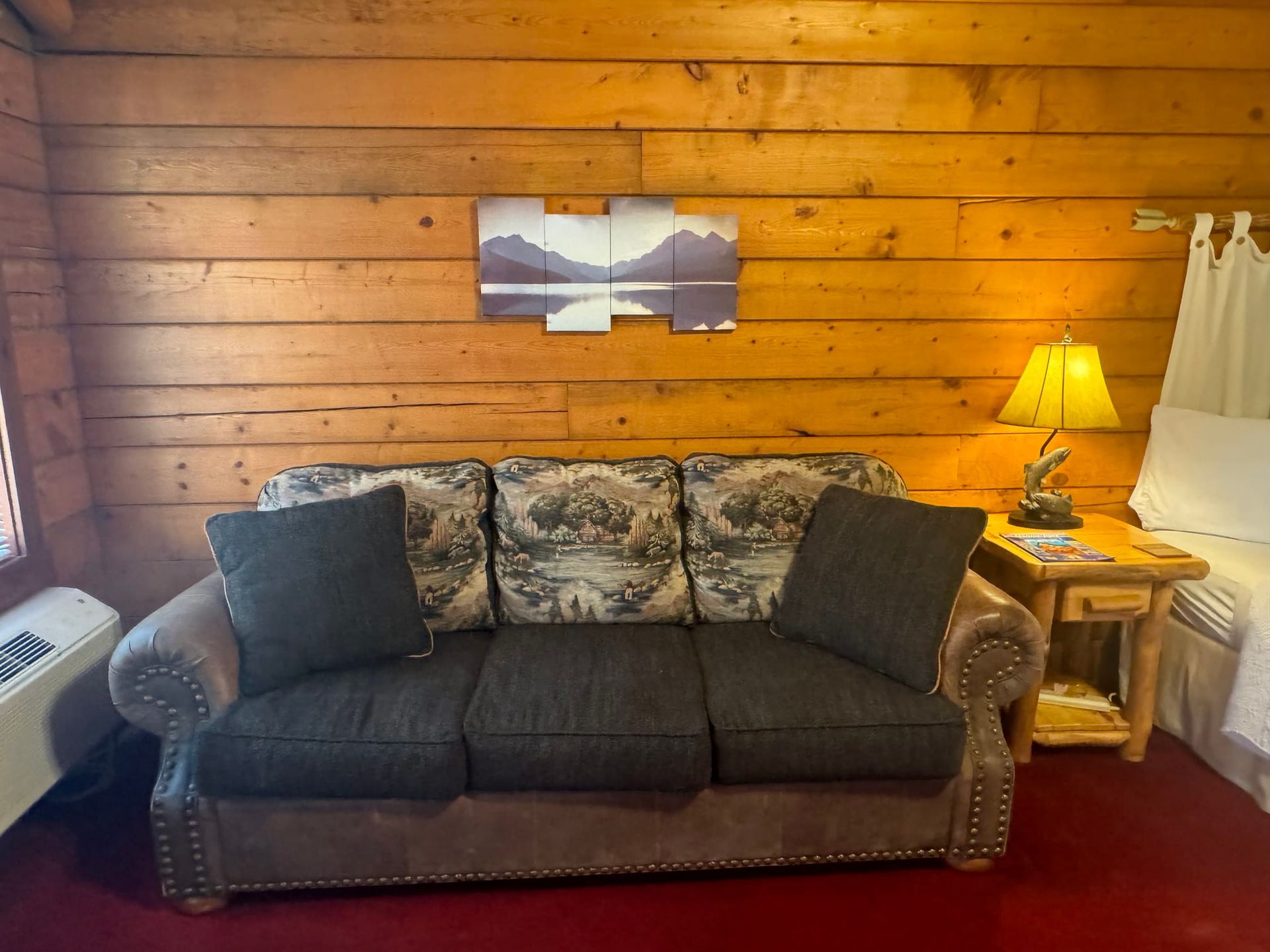 A couch is sitting in a room with a wooden wall.
