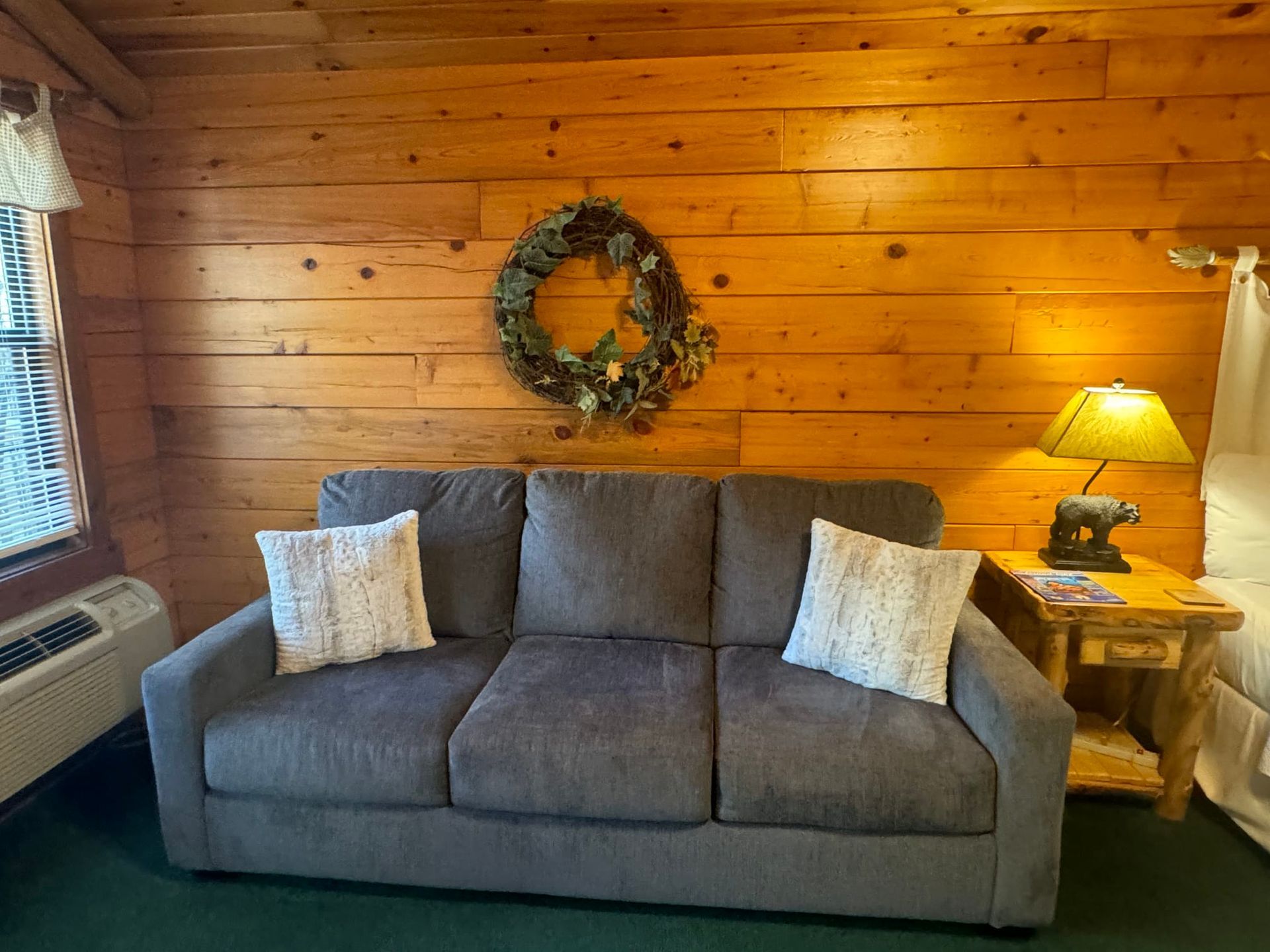 A couch is sitting in a living room with a wooden wall.