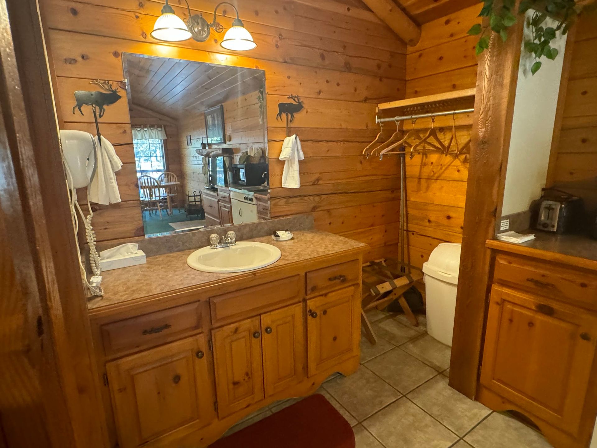 A bathroom in a log cabin with a sink , toilet and mirror.