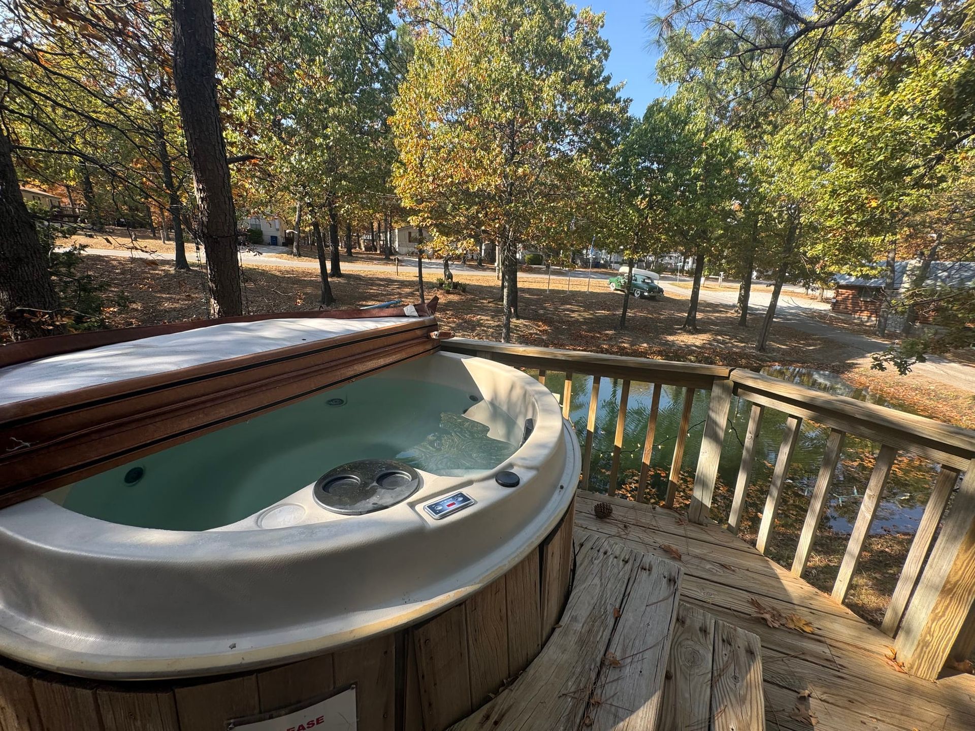 A hot tub is sitting on a wooden deck next to a lake.