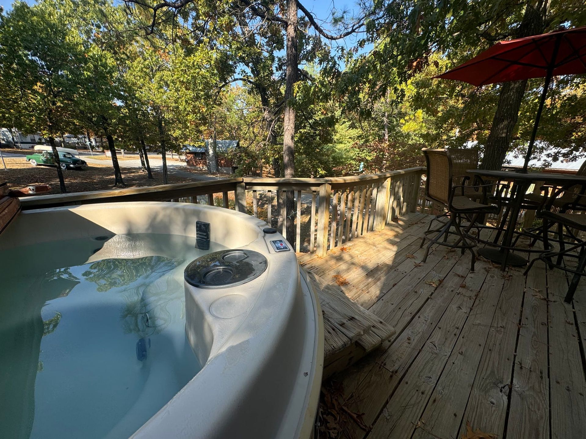 A hot tub is sitting on a wooden deck surrounded by trees.