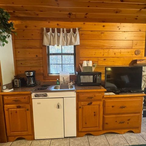 A kitchen with a stove , sink , microwave and television