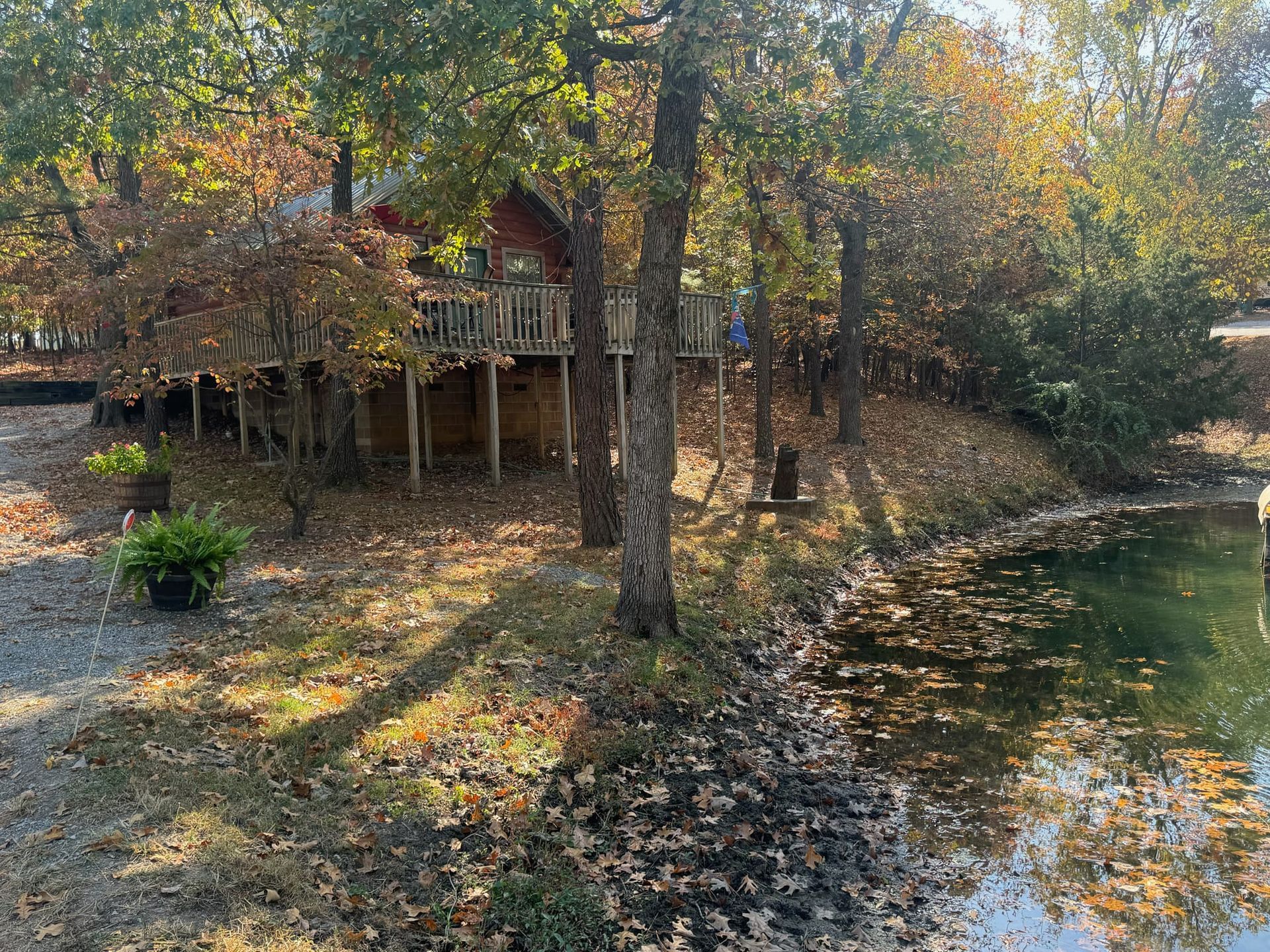 A house is sitting on top of a hill next to a river surrounded by trees.