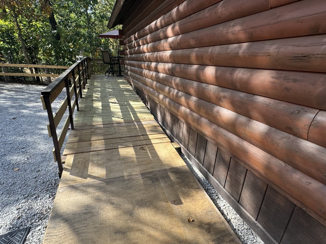 A wooden walkway leading to the side of a log cabin.