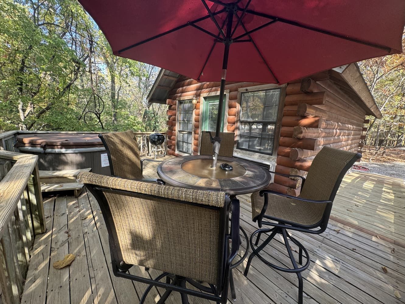 A wooden deck with a table and chairs under an umbrella.