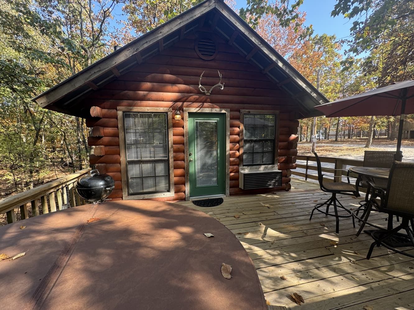 A small log cabin with a hot tub on the deck.
