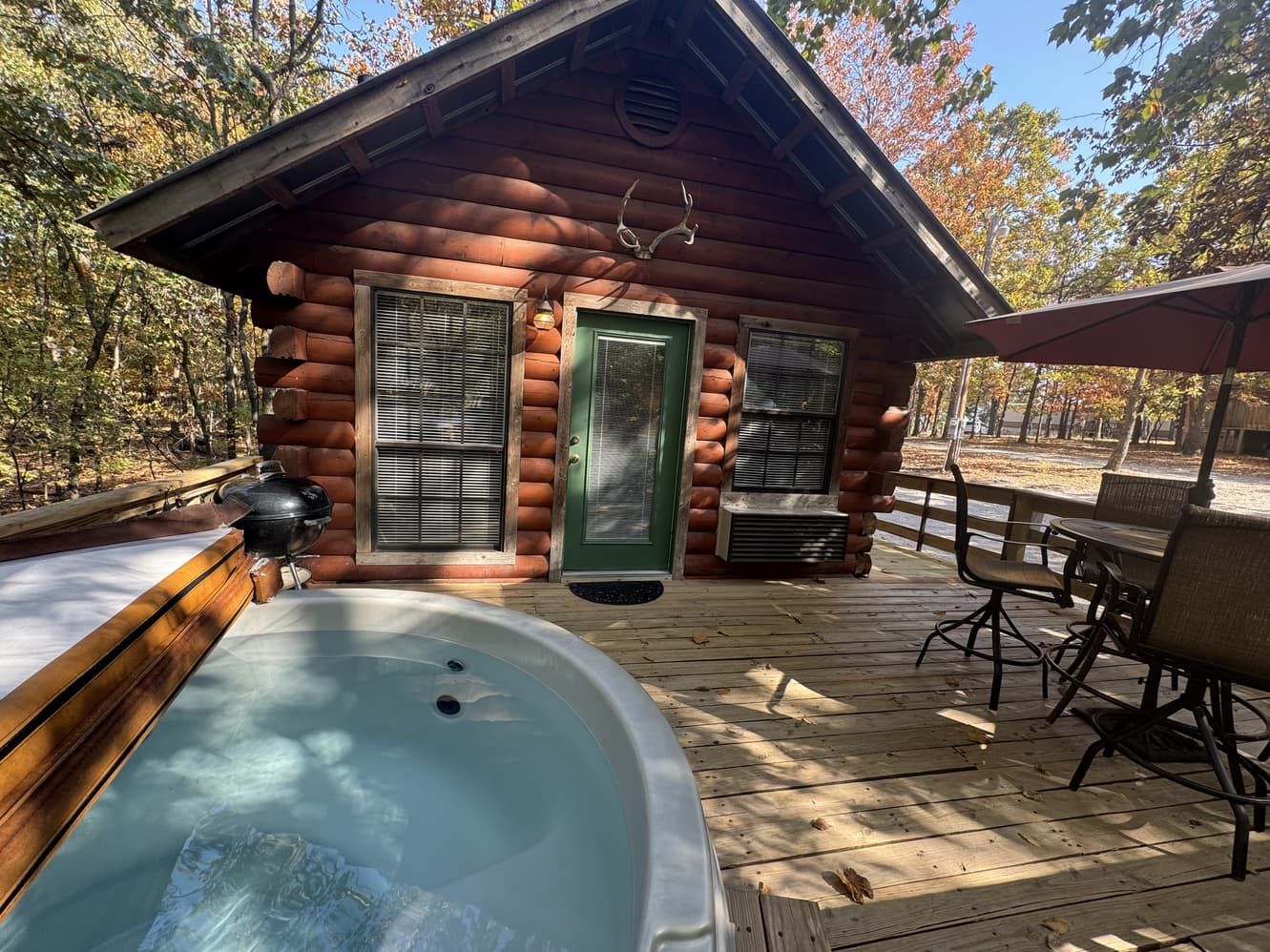 A log cabin with a hot tub on the deck.