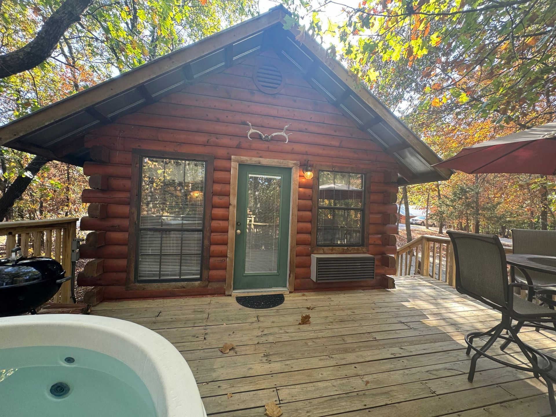 A log cabin with a hot tub on the deck.
