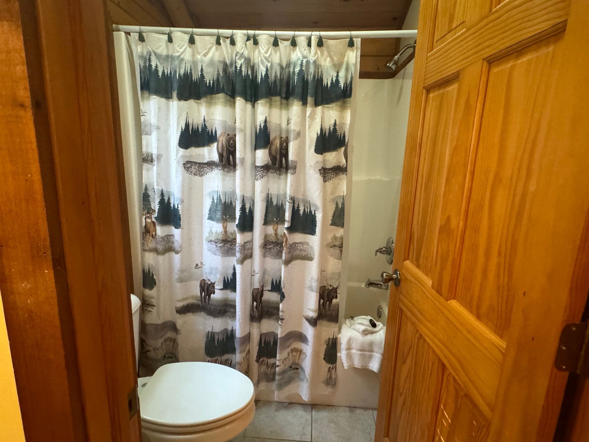 A bathroom with a toilet , shower curtain and bathtub.