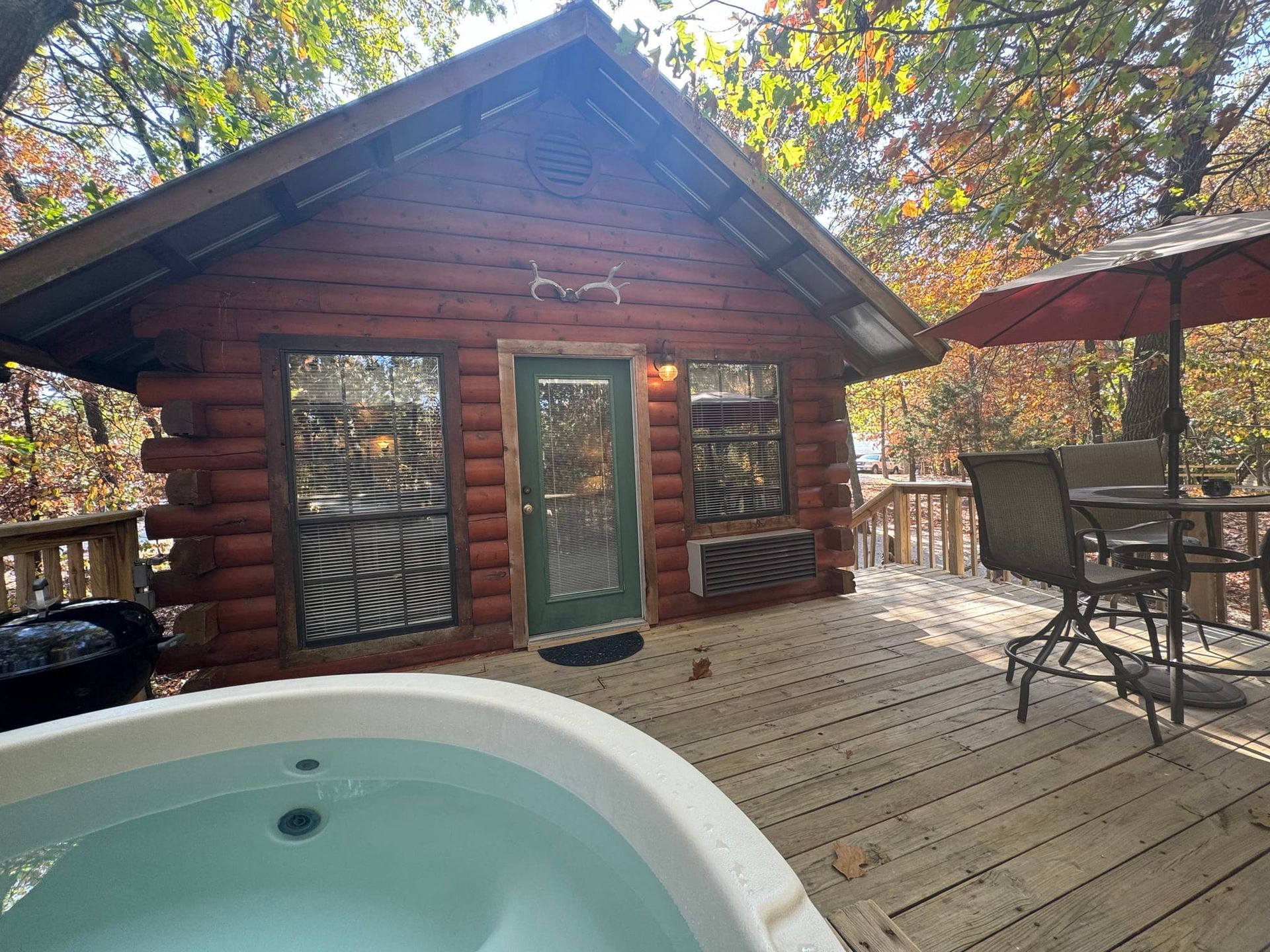 A log cabin with a hot tub on the deck.