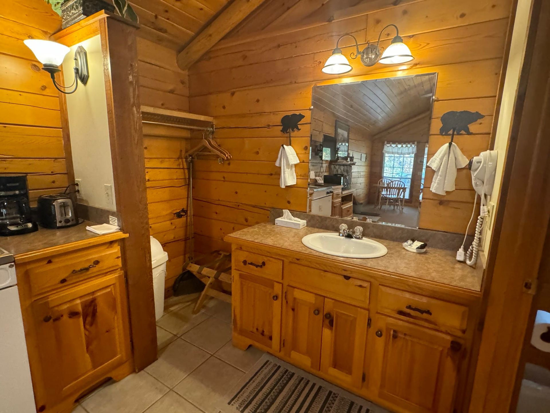 A bathroom in a log cabin with a sink , toilet and mirror.