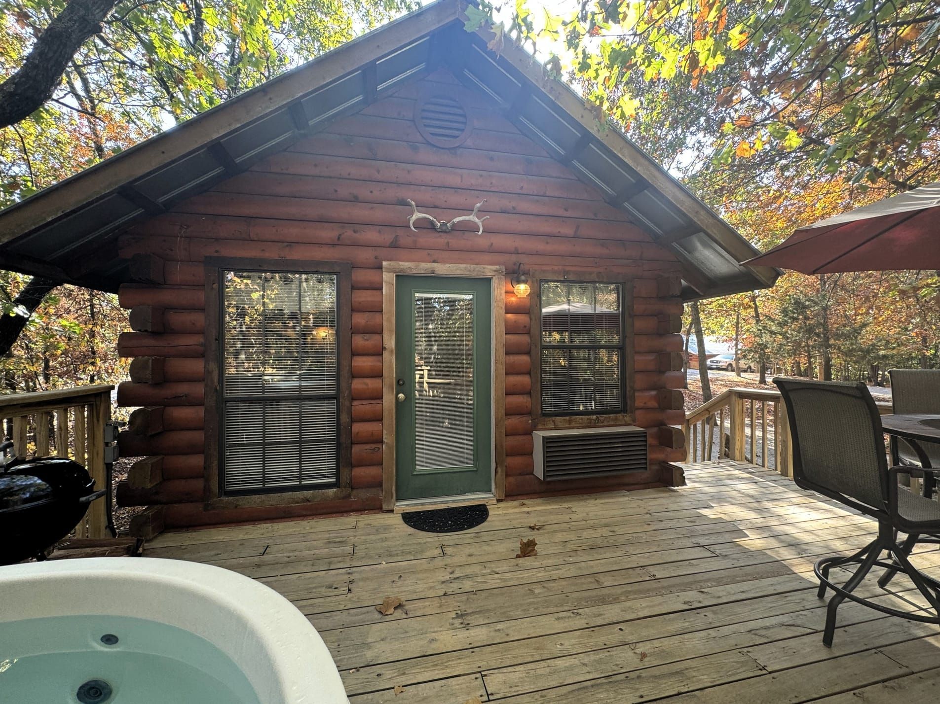 A small log cabin with a hot tub on the deck.