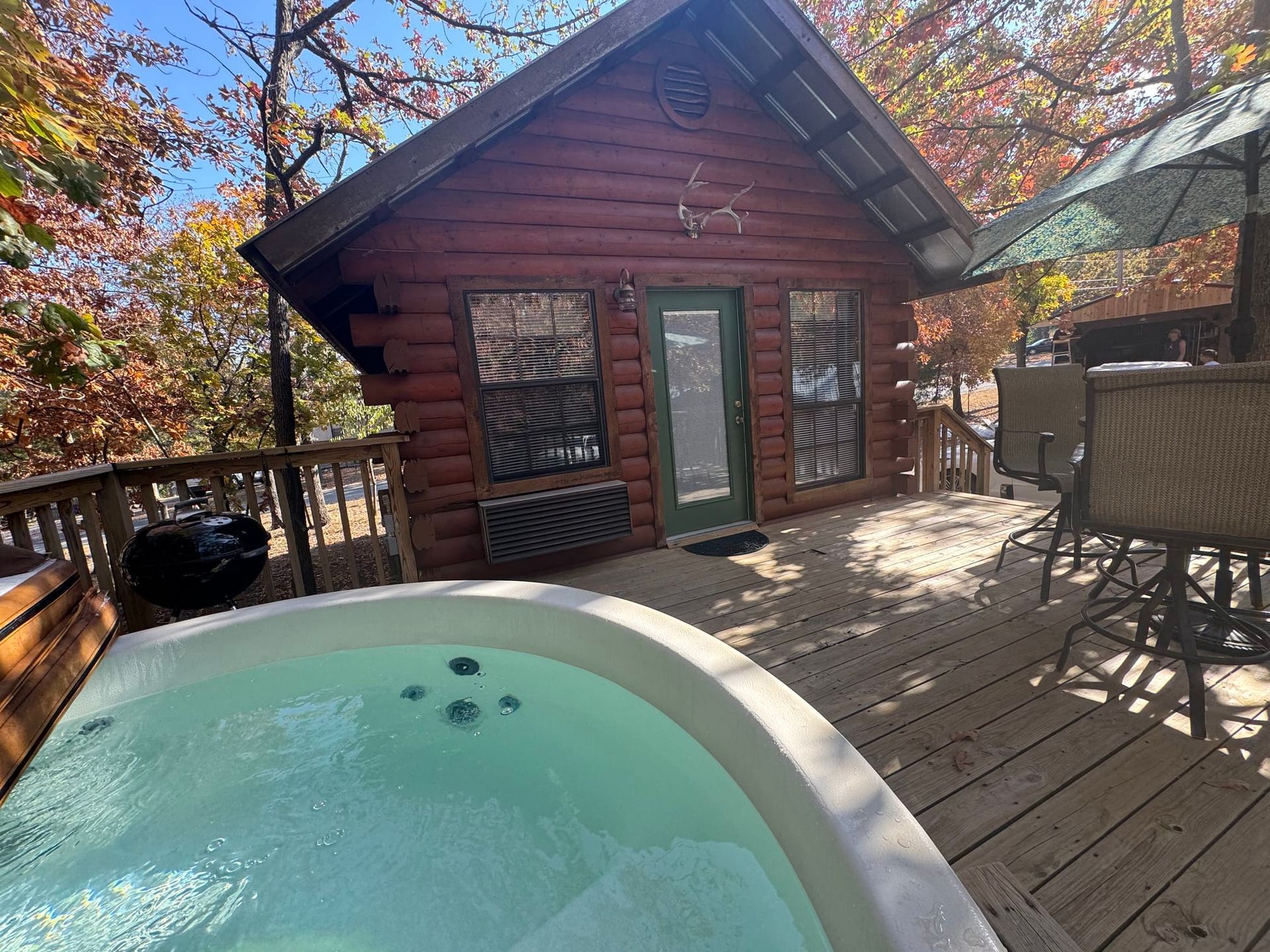 There is a hot tub on the deck of a log cabin.