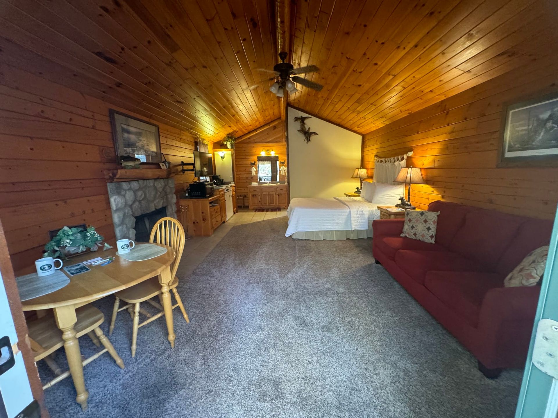 A cabin with a bed , couch , table and chairs.