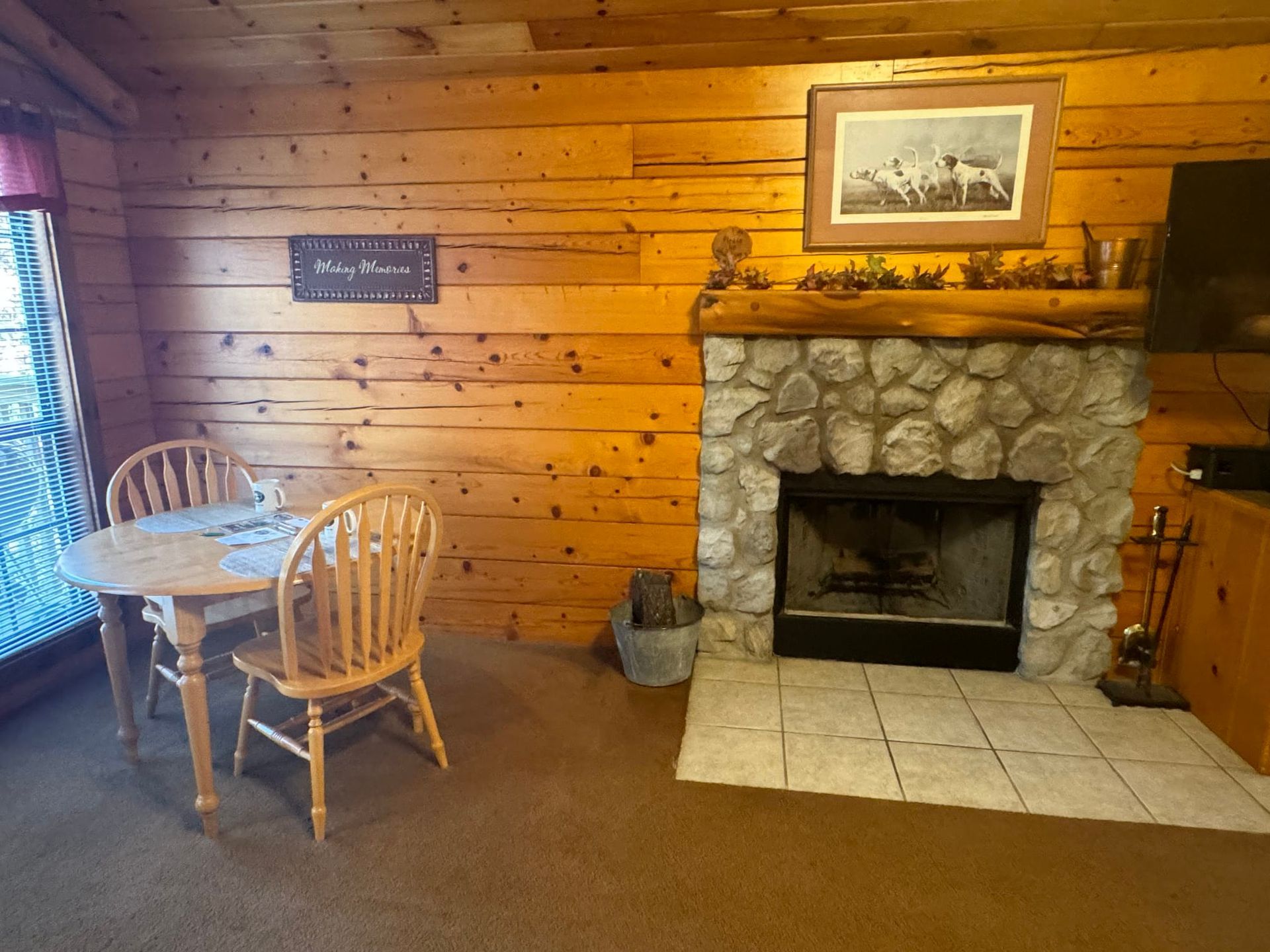 A living room with a stone fireplace and a table and chairs