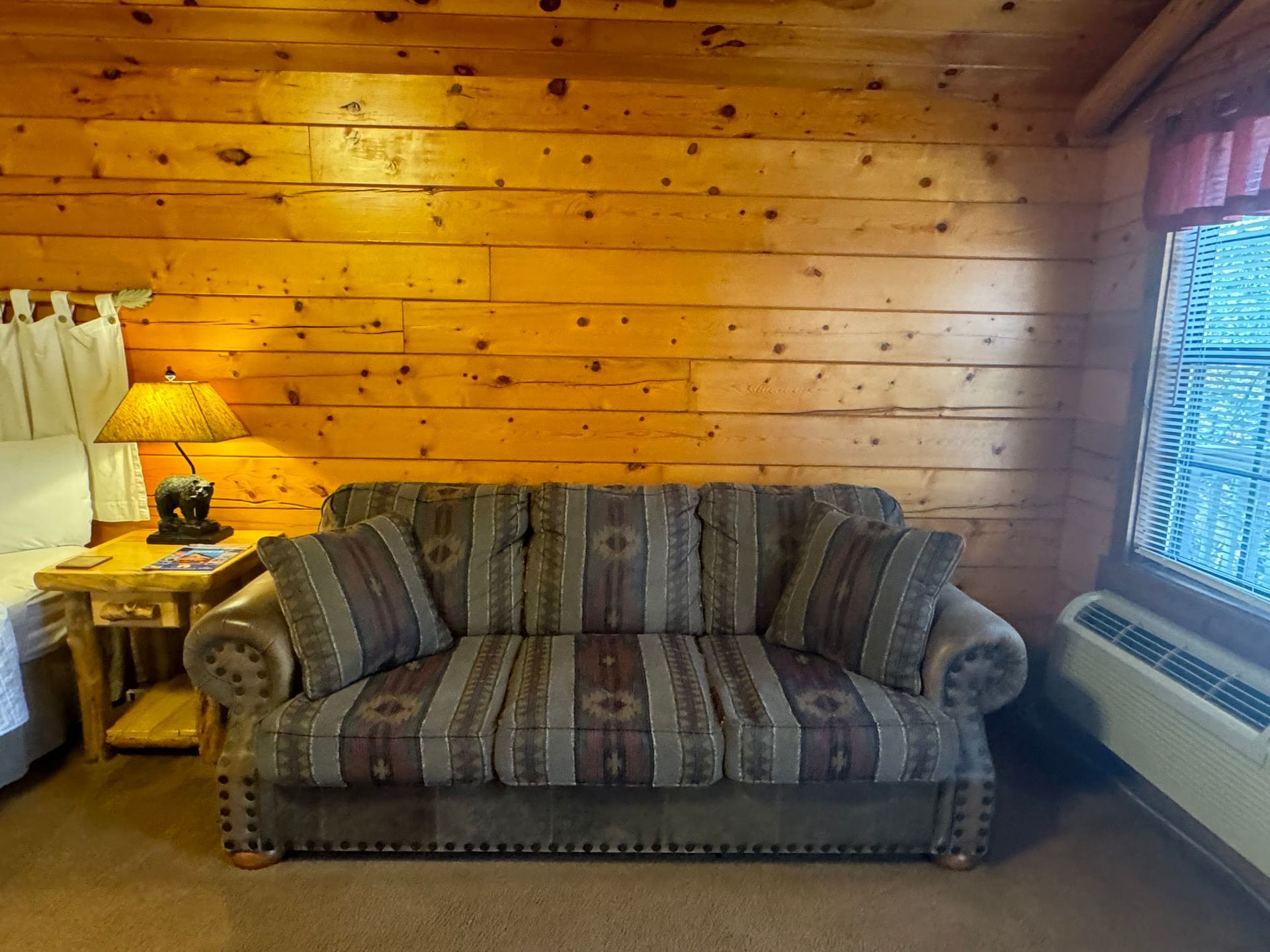 A couch in a room with a wooden wall