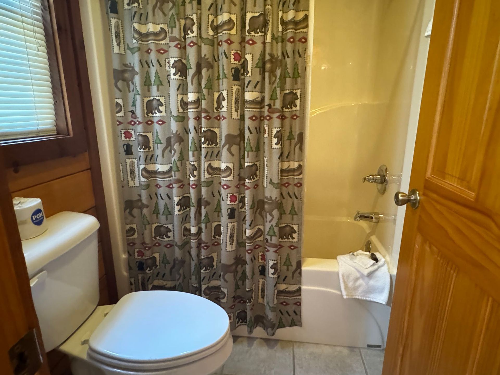 A bathroom with a toilet and a shower curtain with animals on it