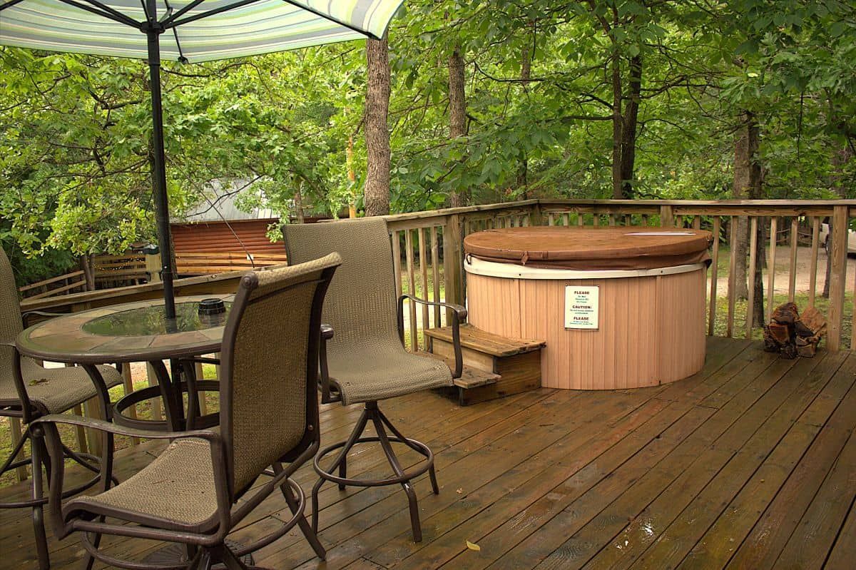 A wooden deck with a table and chairs and a hot tub.