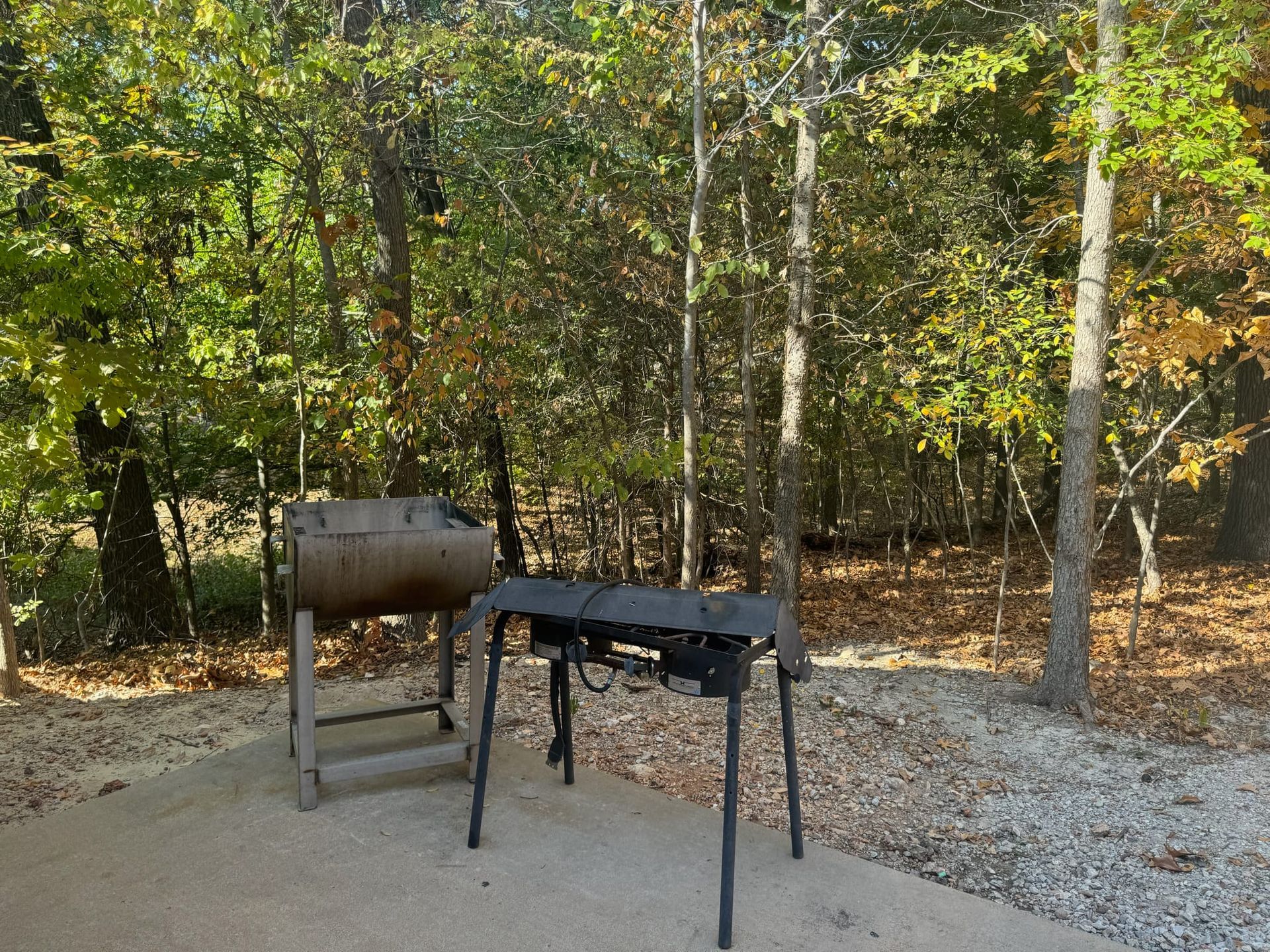 A barbecue grill is sitting in the middle of a forest.
