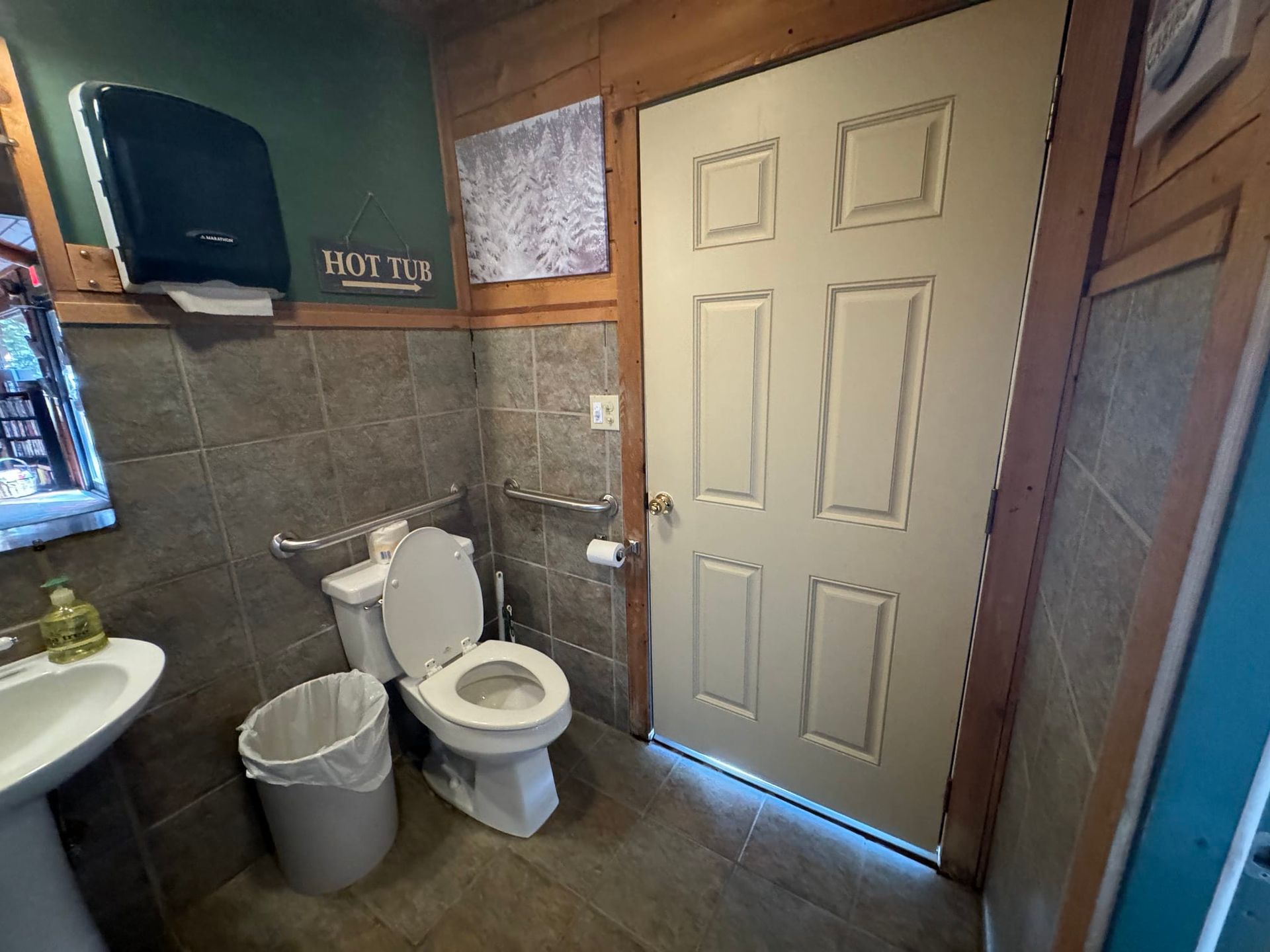 A bathroom with a toilet , sink and trash can
